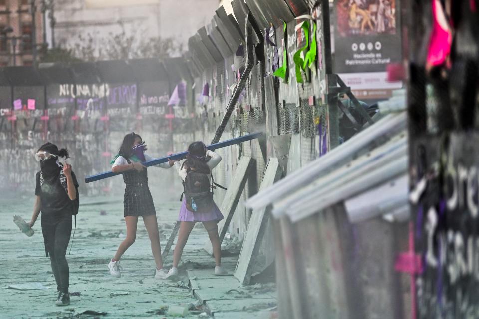 Women clash with the police, behind a fence in front of the National Palace, as they protest during a demonstration to commemorate the International Women's Day  in Mexico City, on March 8, 2021. (Photo by PEDRO PARDO / AFP) (Photo by PEDRO PARDO/AFP via Getty Images)