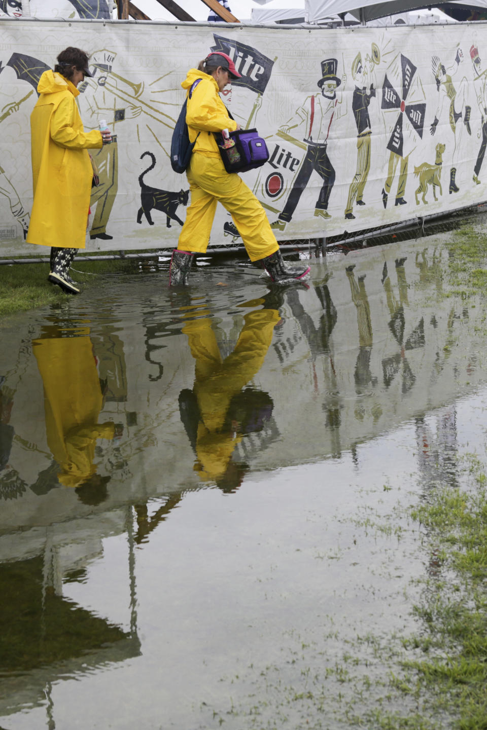 Festival-goers wear rain gear as they roam the flooded grounds at the New Orleans Jazz & Heritage Festival New Orleans, Thursday, April 25, 2019. The opening was delayed by heavy rain. (AP Photo/Doug Parker}