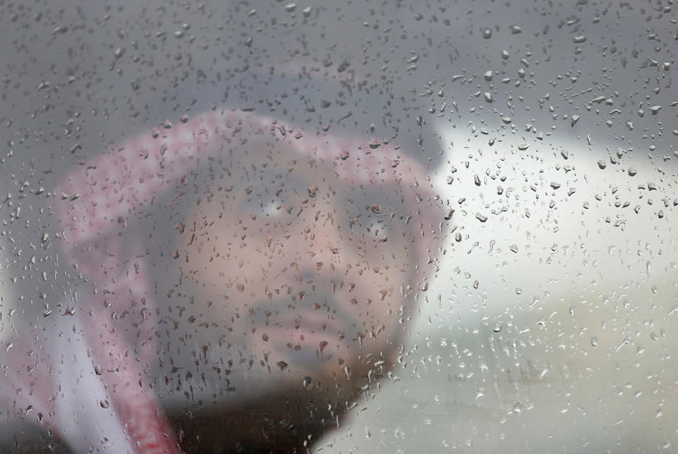 Saudi man peeks out a window during rain in Riyadh