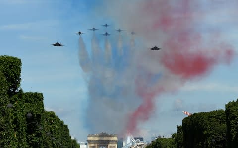F22 and F16 Thunderbirds of US Air Force, fly over Paris during the annual Bastille Day military parade on the Champs-Elysees avenue in Paris  - Credit: AFP