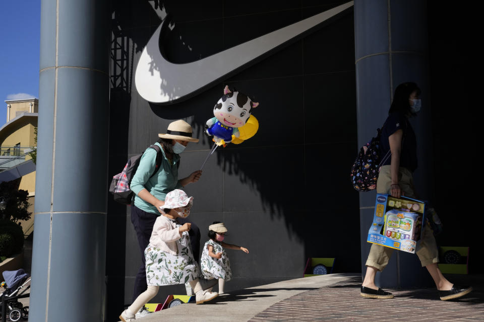 A woman and children wearing masks pass by Nike store in Beijing on Thursday, June 3, 2021. The Chinese government has accused H&M, Nike, Zara and other brands of importing unsafe or poor quality children's clothes and other goods, adding to headaches for foreign companies after Beijing attacked them over complaints about possible forced labor in the country's northwest. (AP Photo/Ng Han Guan)