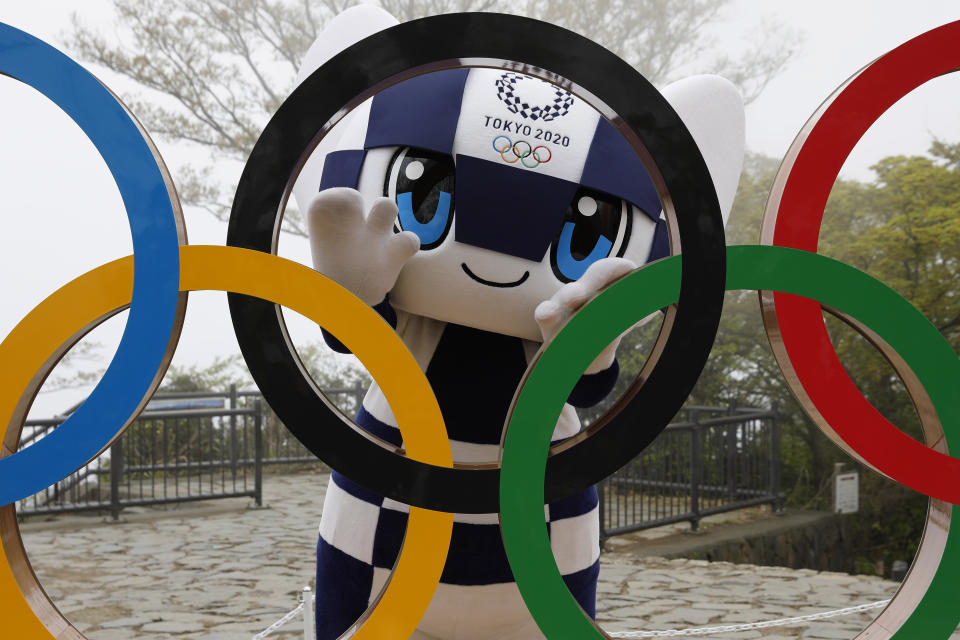 FILE - In this April 14, 2021, file photo, Tokyo 2020 Olympic Games mascot Miraitowa poses with a display of Olympic Symbol after an unveiling ceremony of the symbol on Mt. Takao in Hachioji, west of Tokyo to mark 100 days before the start of the Olympic Games. Japan is set to raise the coronavirus alert level in Tokyo’s three neighboring prefectures and a forth area in central Japan to allow tougher measures as a more contagious coronavirus variant spreads and doubts are growing whether the Olympics can go ahead. (Kim Kyung-Hoon/Pool Photo via AP)