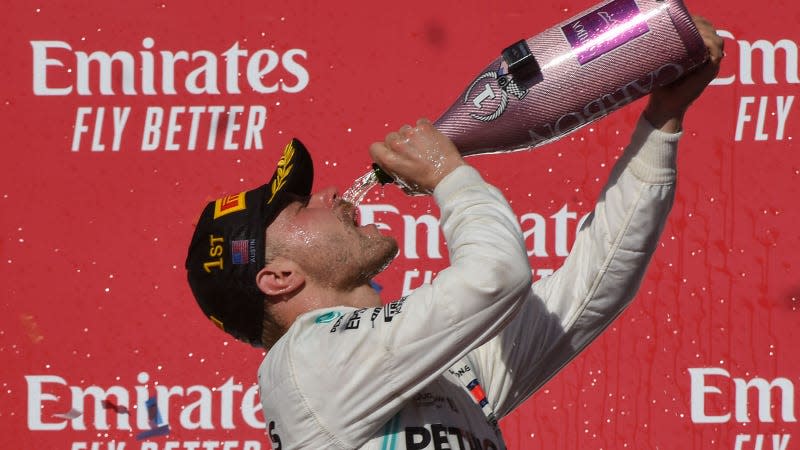 A photo of Valtteri Bottas drinking Champagne on the F1 podium. 