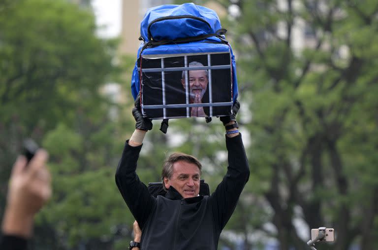 El presidente brasileño y candidato a la reelección, Jair Bolsonaro, sostiene una bolsa con la imagen Lula preso 