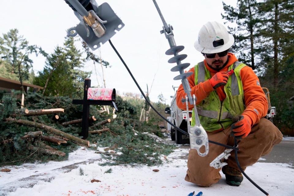 PHOTO: A worker from PG&E works to install a new power line as crews work on restoring power to the area after a storm, Jan. 16, 2024, in Lake Oswego, Ore. (Jenny Kane/AP)