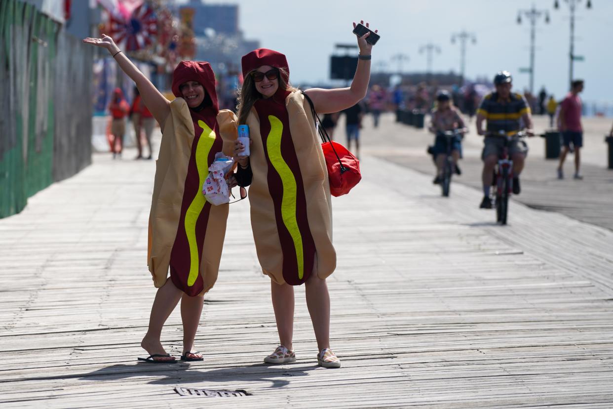 Spectators wearing hot dog costumes walk on the boardwalk prior to the 2021 Nathan's Famous 4th Of July International Hot Dog Eating Contest on July 4, 2021, in New York City.