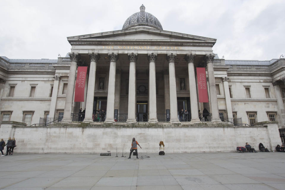 A street performer stands in front of the National Gallery in a nearly empty Trafalgar Square.