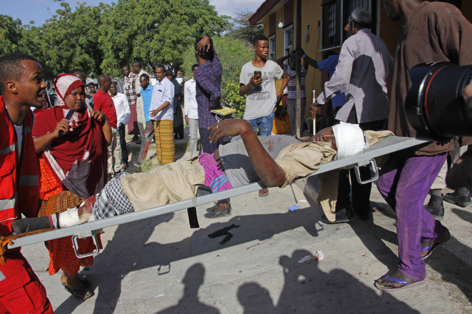Medical personnel carry a civilian who was wounded in suicide car bomb attack at check point in Mogadishu, Somalia, Saturday, Dec, 28, 2019. A police officer says a car bomb has detonated at a security checkpoint during the morning rush hour in Somalia's capital. (AP Photo/Farah Abdi Warsame)