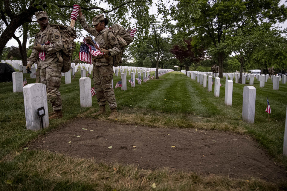 Members of the 3rd U.S. Infantry Regiment also known as The Old Guard, place flags in front of each headstone for "Flags-In" at sunrise at Arlington National Cemetery in Arlington, Thursday, May 25, 2023, to honor the Nation's fallen military heroes ahead of Memorial Day. (AP Photo/Andrew Harnik)