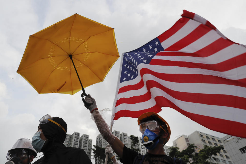 Protesters with protection gear hold up an umbrella and an American flag as they march through Sha Tin District in Hong Kong, Sunday, July 14, 2019. Opponents of a proposed Hong Kong extradition law have begun a protest march, adding to an outpouring of complaints the territory's pro-Beijing government is eroding its freedoms and autonomy. (AP Photo/Kin Cheung)