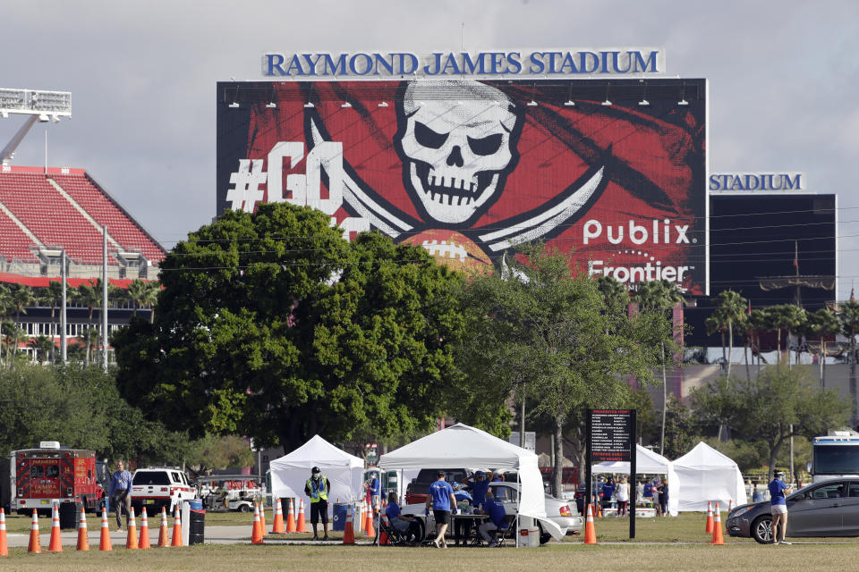 White tents are setup for COVID-19 tests in the parking lot with the Raymond James Stadium sign in the background.