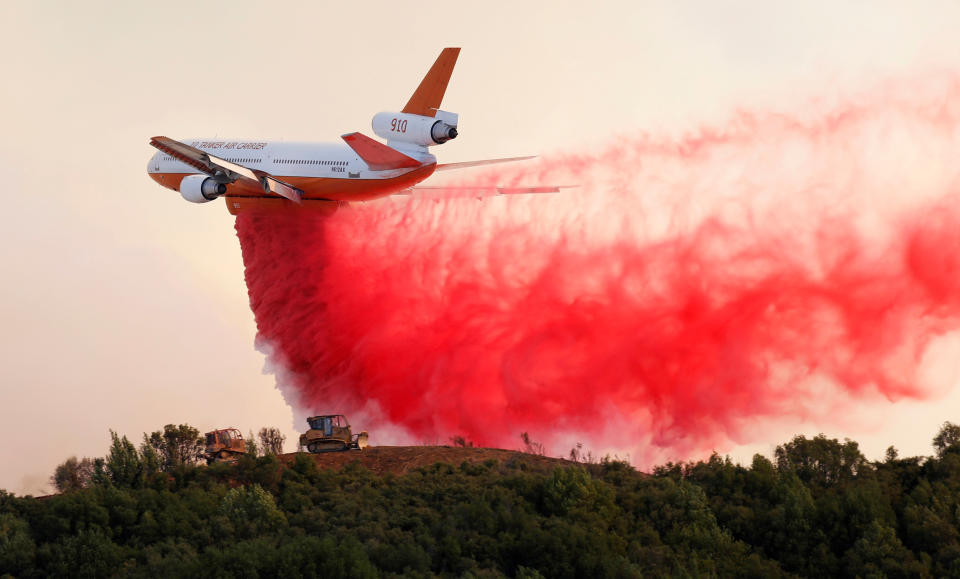 A DC-10 air tanker drops fire retardant along the crest of a hill to protect the two bulldozers below that were cutting fire lines near the River fire on Thursday. (Photo: Fred Greaves / Reuters)