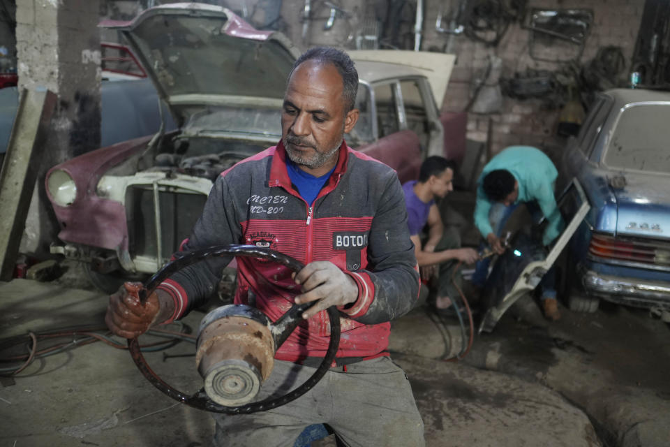 Mechanics work on a 1976 Mercedes at a private car collector's lot in El Saff city in the Giza, just outside Cairo, Egypt. Friday, April 8, 2022. Egyptian businessman and a classic car collector Mohamed Wahdan says he has accumulated more than 250 vintage, antique and classic cars over the past 20 years. (AP Photo/Amr Nabil)