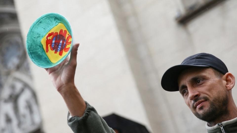 Un hombre en Brasil muestra un plato que tiene escrita la palabra "hambre" en portugués.