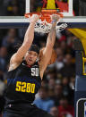 Denver Nuggets forward Aaron Gordon hangs from the rim after dunking against the Phoenix Suns during the first half of an NBA basketball game Wednesday, March 27, 2024, in Denver. (AP Photo/David Zalubowski)