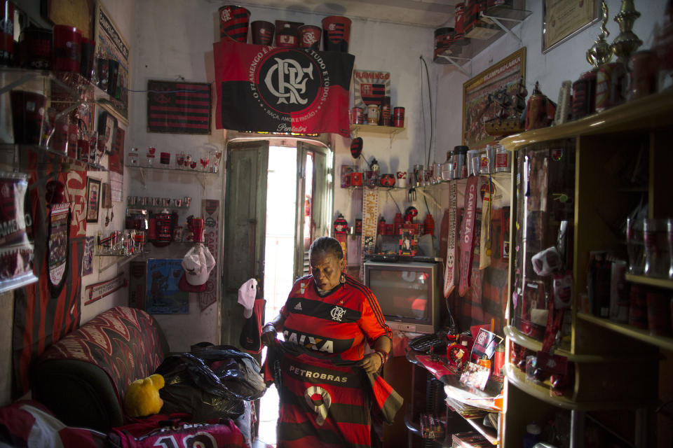 In this April 28, 2014 photo, Maria Boreth de Souza, alias Zica, organizes her favorite Flamengo jerseys inside her home full of her soccer team's memorabilia in the Olaria neighborhood of Rio de Janeiro, Brazil. Souza is known as "Zica" in honor of former Brazilian football great Zico, whose mother persuaded her to leave the streets and return to her home 46 years ago, where she cared for her parents. (AP Photo/Leo Correa)