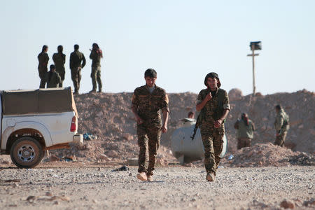 Syrian Democratic Forces (SDF) fighters walk with their weapons, north of Raqqa city, Syria November 6, 2016. REUTERS/Rodi Said