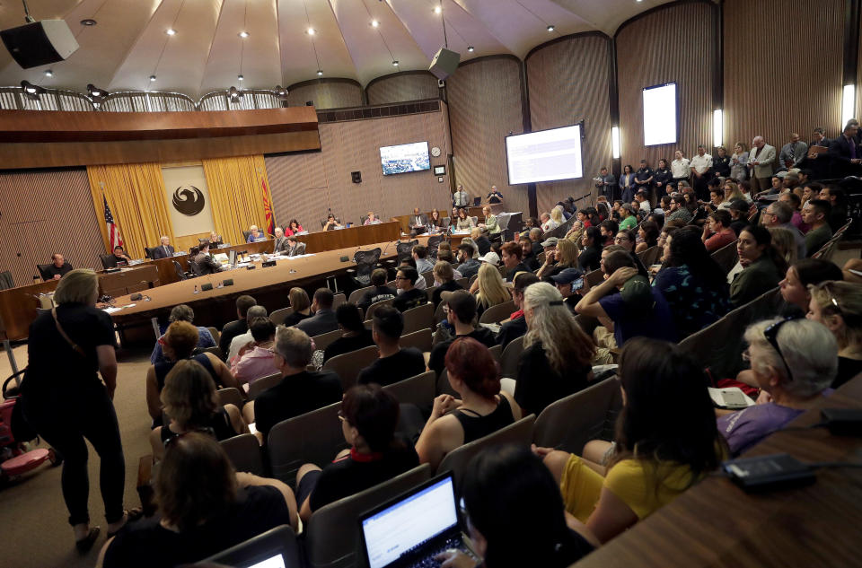 Protesters angered by a video of Phoenix officers who pointed guns and yelled obscenities at a black family they suspected of shoplifting gather inside City Council chambers, Wednesday, June 19, 2019, in Phoenix to demand reforms. Speakers called on the council to fire the officers involved in the videotaped incident and to create a board of civilians to oversee changes in department procedures. (AP Photo/Matt York)