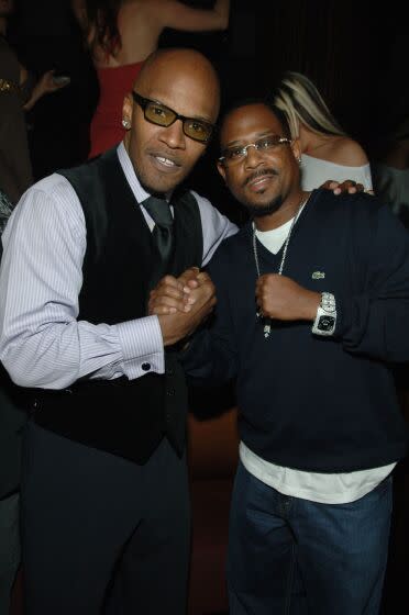 Jamie Foxx and Martin Lawrence clasp hands and look straight ahead