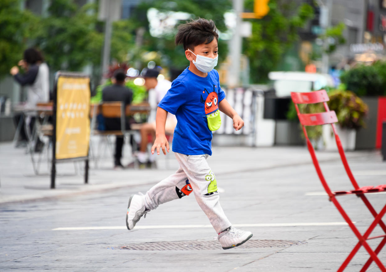 NEW YORK, NEW YORK - AUGUST 16: A kid wears a protective face mask in Times Square as the city continues Phase 4 of re-opening following restrictions imposed to slow the spread of coronavirus on August 16, 2020 in New York City. The fourth phase allows outdoor arts and entertainment, sporting events without fans and media production. (Photo by Noam Galai/Getty Images)