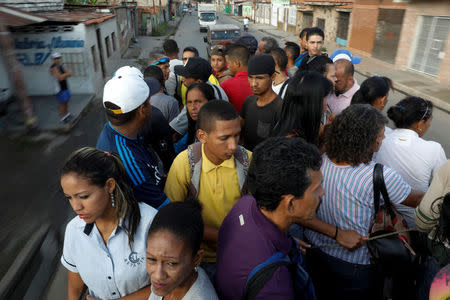 Commuters ride on a cargo truck used as public transportation in Valencia, Venezuela. REUTERS/Marco Bello