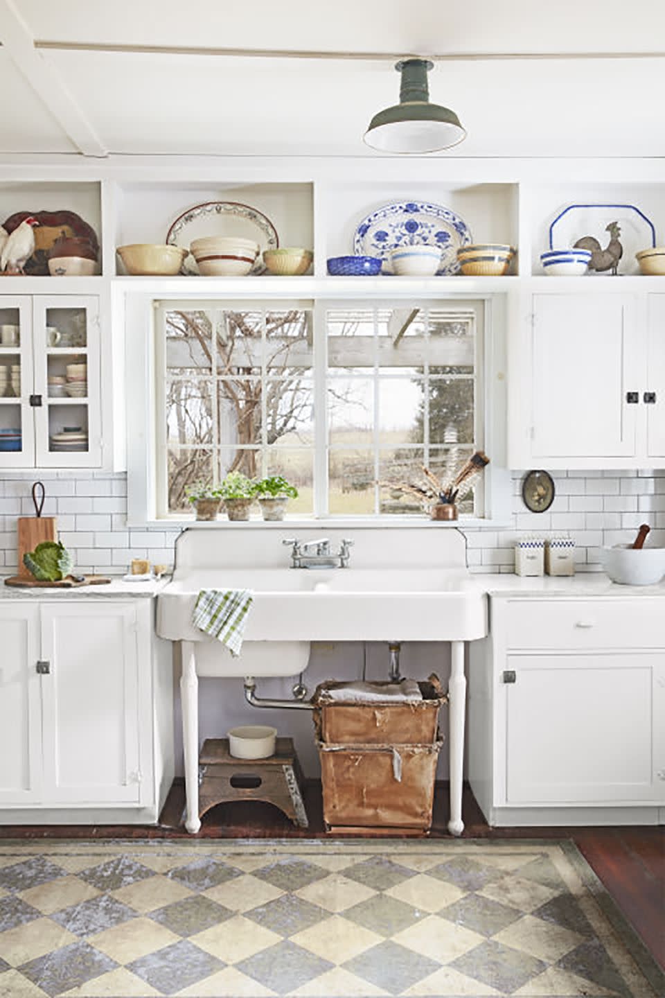 a white antique sink is nestled between two white cabinets and under a window in a farmhouse kitchen