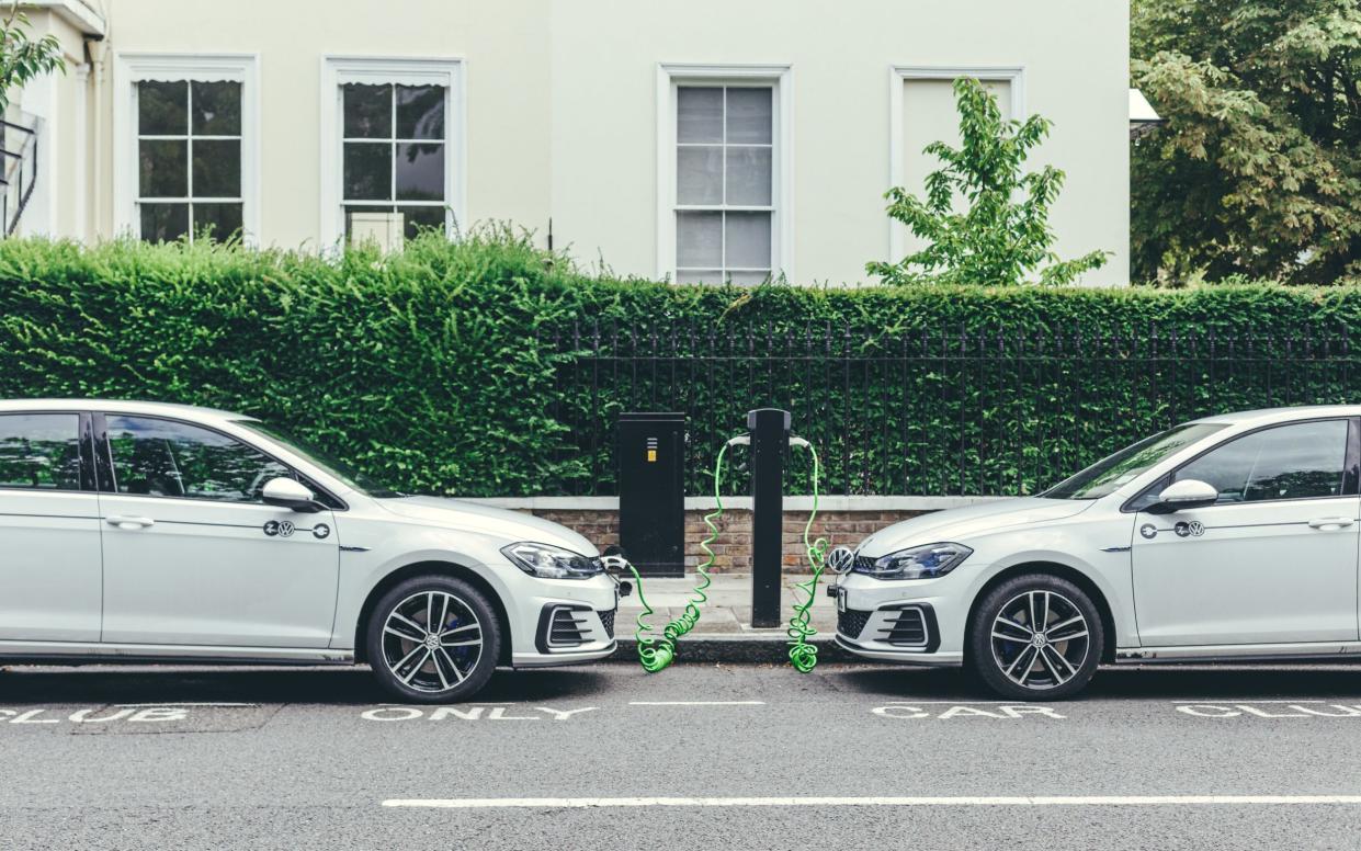 two white Volkswagen Golf GTE cars charging at a charging point on a street in London