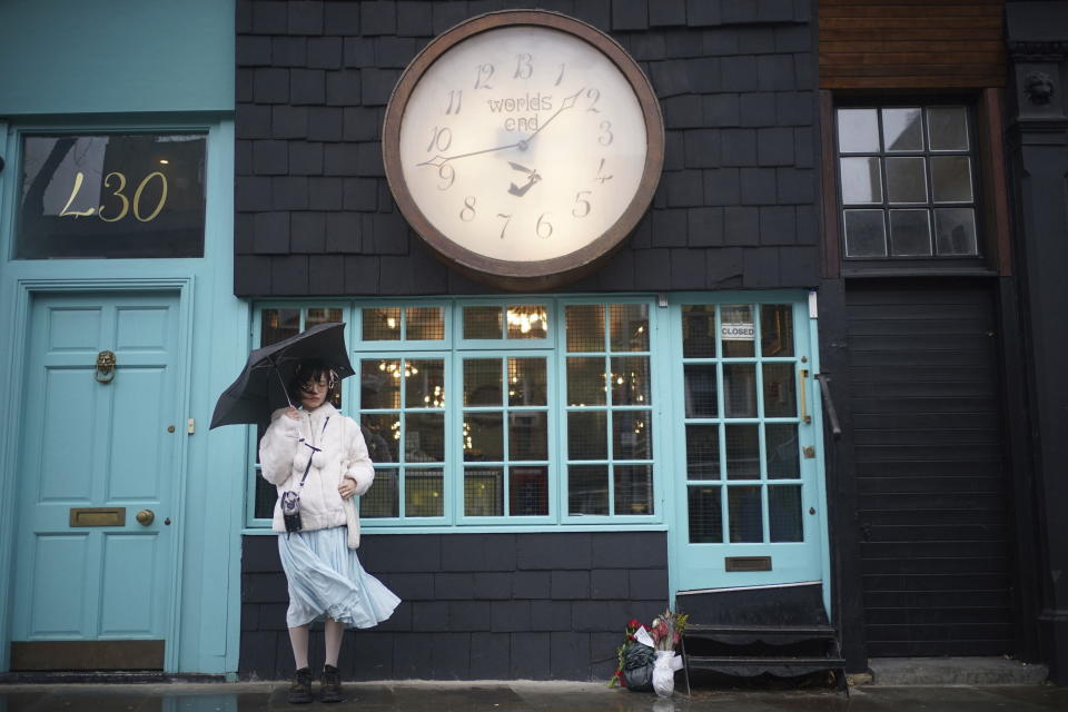 A woman stands by floral tributes outside Vivienne Westwood Worlds End shop, in London, Friday, Dec. 30, 2022. English designer Vivienne Westwood has died at 81. Her fashion house announced her death Thursday, Dec. 29, 2022 on its social media platforms, saying she died peacefully in South London surrounded by friends and family. A cause was not immediately disclosed. (Yui Mok/PA via AP)