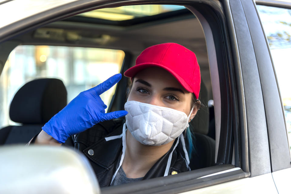 Woman in the car with protective glove and facial mask.Health protection. Hands with blue gloves.She sprinkling disinfectant and cleaning the car.