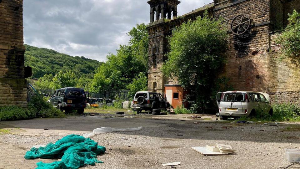 Three burnt-out vehicles overshadowed by a mill tower