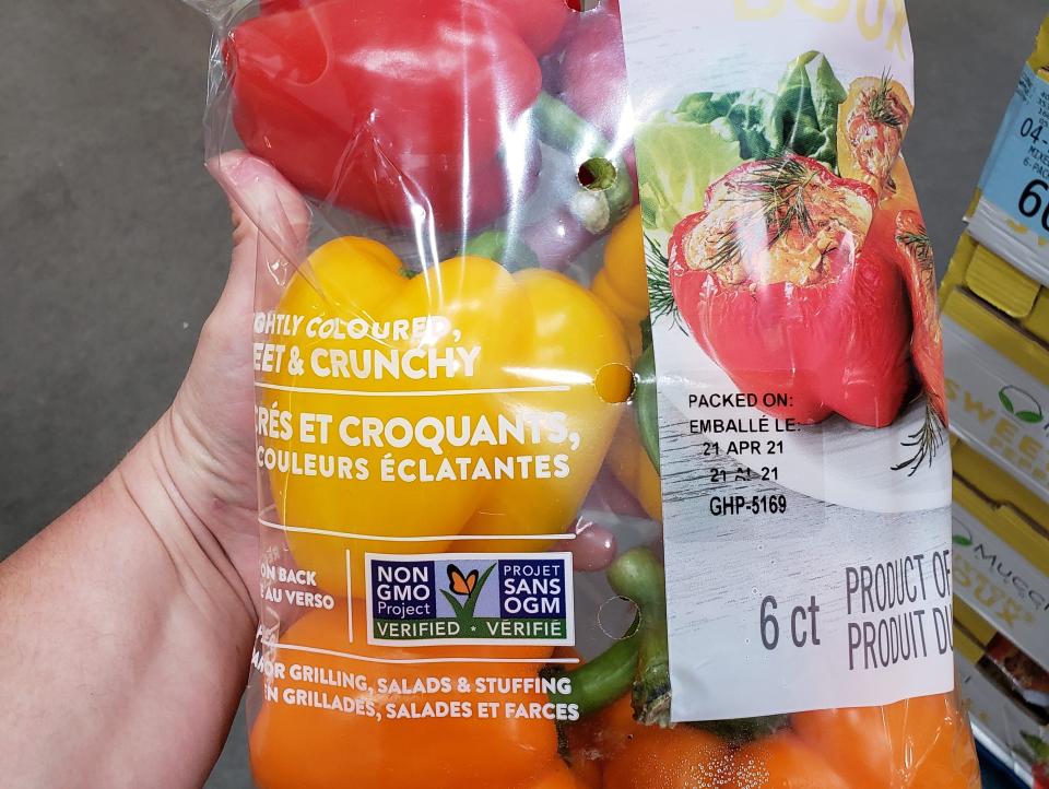 hand holding a bulk bag of tri-colored bell peppers at costco