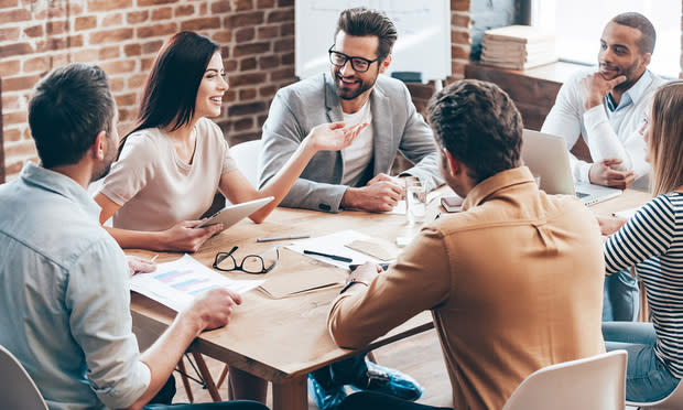 Making great decisions. Young beautiful woman gesturing and discussing something with smile while her coworkers listening to her sitting at the office table, talking, laughing, smiling, happy, excited, friendly