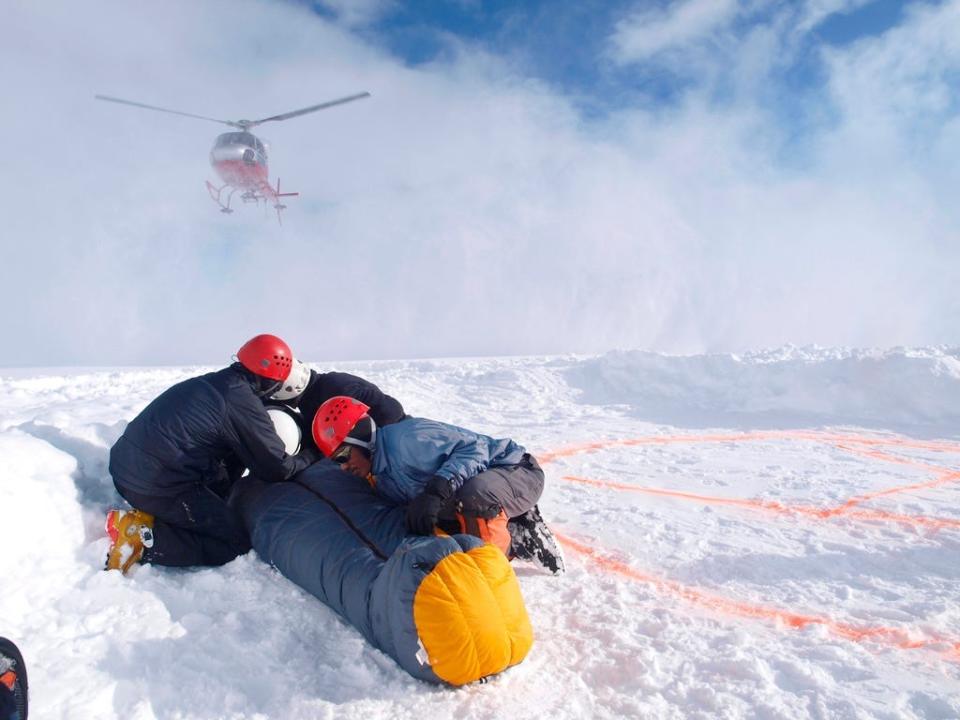 Mountain Rescuers are protecting a victim for the down wind of the landing helicopter at 14.000 foot on Denali.