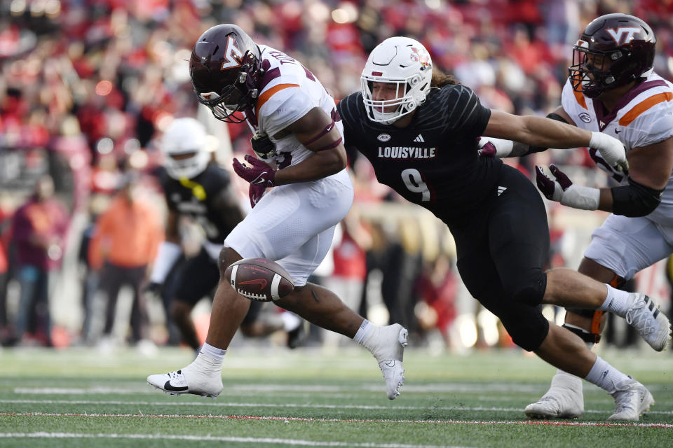 Louisville defensive lineman Ashton Gillotte (9) punches the ball away from Virginia Tech running back Bhayshul Tuten (33) during the second half of an NCAA college football game in Louisville, Ky., Saturday, Nov. 4, 2023. Louisville won 34-3. (AP Photo/Timothy D. Easley)