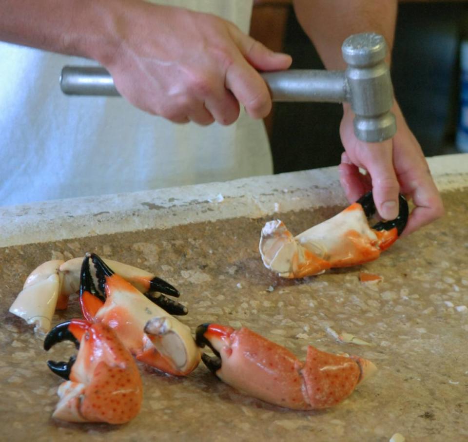 Chris Burns cracks stone crab claws for a customer at the Star Fish Company Seafood Market and Restaurant in Cortez.