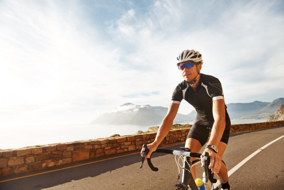 a man in athletic gear riding a bicycle on a road overlooking the coast