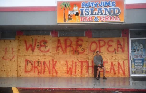 PHOTO: Tom Norgard has a smoke as he sits outside watching the weather from Hurricane Ian at Salty Jim's Island Bar & Grill in Sarasota, Fla., Sept. 28, 2022. The bar plans to stay open as long as possible during the storm. (Mike Lang/Sarasota Herald-Tribune via USA Today Network)