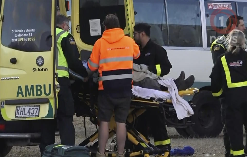 In this image made from video, rescue crews tend to victims in a hot air balloon crash near Arrowtown, New Zealand, Friday, July 9, 2021. The balloon crashed as it was about to land on Friday, injuring all 11 people on board, including two who suffered serious injuries and were airlifted to a hospital, according to authorities and the ballooning company. (TVNZ via AP)