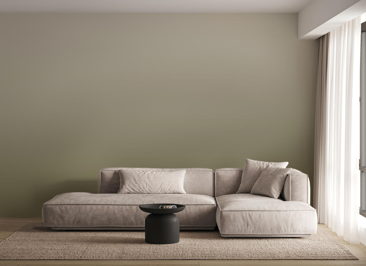  A minimalist living room with a green ombre wall, a cream L-shaped sofa, and a jute rug. 