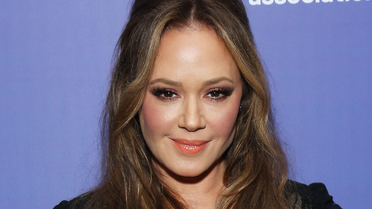 leah remini posing for a photo in front of a purple backdrop