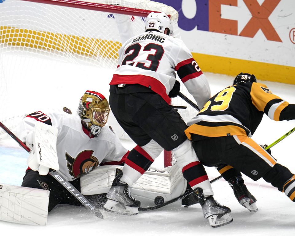 Pittsburgh Penguins' Jake Guentzel (59) cannot get a shot pass Ottawa Senators goaltender Joonas Korpisalo (70) with Senators' Travis Hamonic (23) defending during the first period of an NHL hockey game in Pittsburgh, on Saturday, Oct. 28, 2023. (AP Photo/Gene J. Puskar)