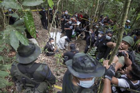 Policemen and reporters monitor as forensic experts dig out human remains near the abandoned human trafficking camp in the jungle close the Thailand border at Bukit Wang Burma in northern Malaysia in this May 26, 2015 file photo. REUTERS/Damir Sagolj/Files