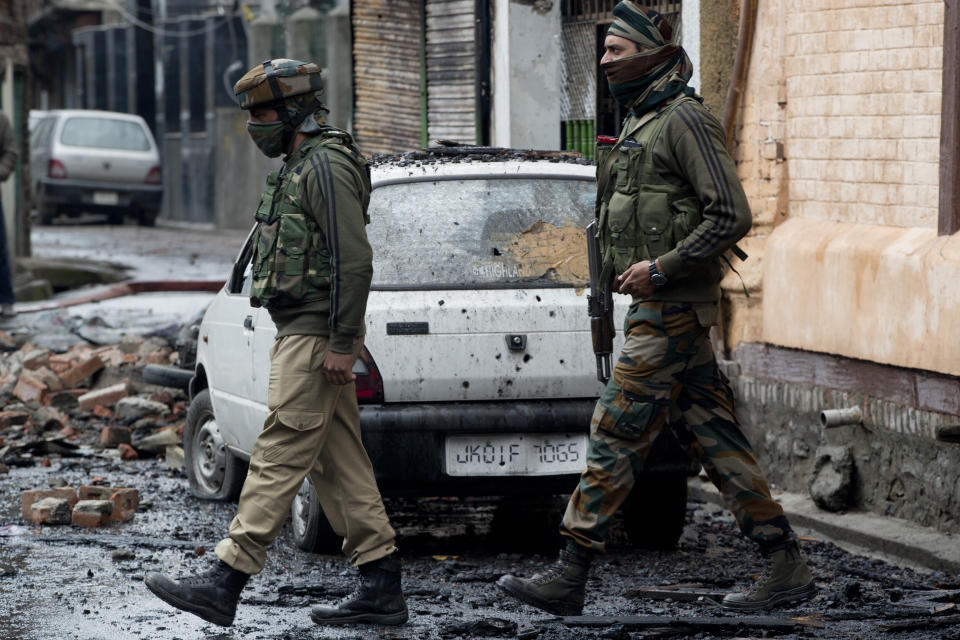 Indian policemen walk past a damaged car outside the house where suspected militants were hiding during a gunbattle with Indian government forces in Srinagar, India, Wednesday, Oct. 17, 2018. Anti-India protests and clashes erupted in the main city of disputed Kashmir on Wednesday shortly after a gunbattle between militants and government forces killed at least two suspected rebels and a counterinsurgency police official. (AP Photo/Dar Yasin)