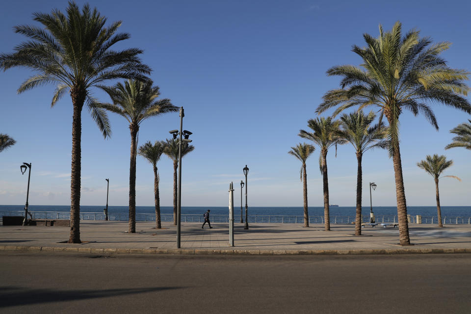 A man walks on a deserted waterfront promenade during a lockdown aimed at curbing the spread of the coronavirus, in Beirut Lebanon, Thursday, Jan. 21, 2021. Authorities on Thursday extended a nationwide lockdown by a week to Feb. 8 amid a steep rise in coronavirus deaths and infections that has overwhelmed the health care system. (AP Photo/Bilal Hussein)