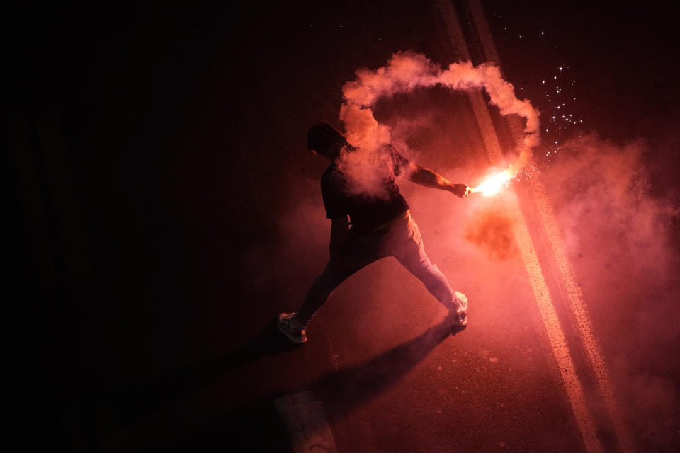 An Israeli holds a flare at a protest against plans by Prime Minister Benjamin Netanyahu's new government to overhaul the judicial system, in Tel Aviv, Israel, Saturday, Feb. 25, 2023. On Tuesday, Netanyahu's government for the first time advanced the plan by securing a preliminary vote at the Knesset, defying a mass uproar among Israelis and calls for restraint from the United States. (AP Photo/Ariel Schalit)