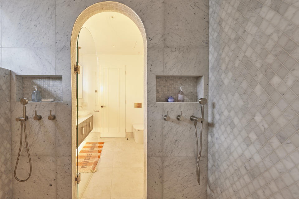 A shot from inside the shower, looking through the arched doorway to the rest of the bathroom. 