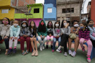 Workers paint the facades of residences in the Paraisopolis favela, as children sit on a bench during the community's centennial celebration, in Sao Paulo, Brazil, Thursday, Sept. 16, 2021. One of the largest favela's in Brazil, home to tens of thousands of residents in the country's largest and wealthiest city, Paraisopolis is grappling with crime and a pandemic that have challenged daily life for many who live there, but organizers say its people have built a vibrant community and are launching a 10-day celebration of its achievements. (AP Photo/Andre Penner)