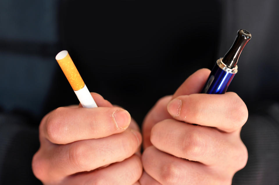 Man holding normal and e-cigarette. (Getty Images)