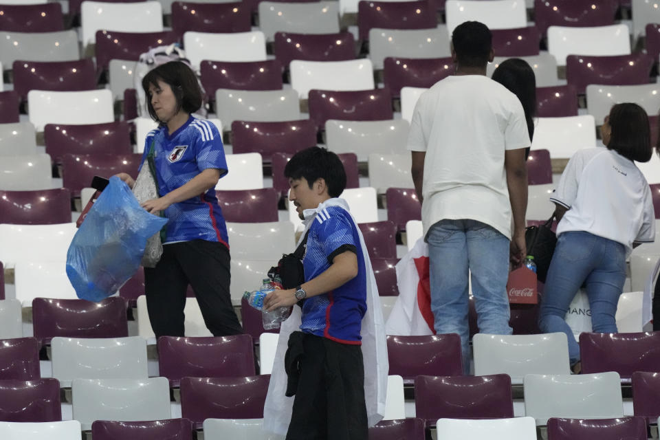 Japan supporters clean the stands at the end of the World Cup group E soccer match between Germany and Japan, at the Khalifa International Stadium in Doha, Qatar, Wednesday, Nov. 23, 2022. Japan won 2-1.(AP Photo/Eugene Hoshiko)