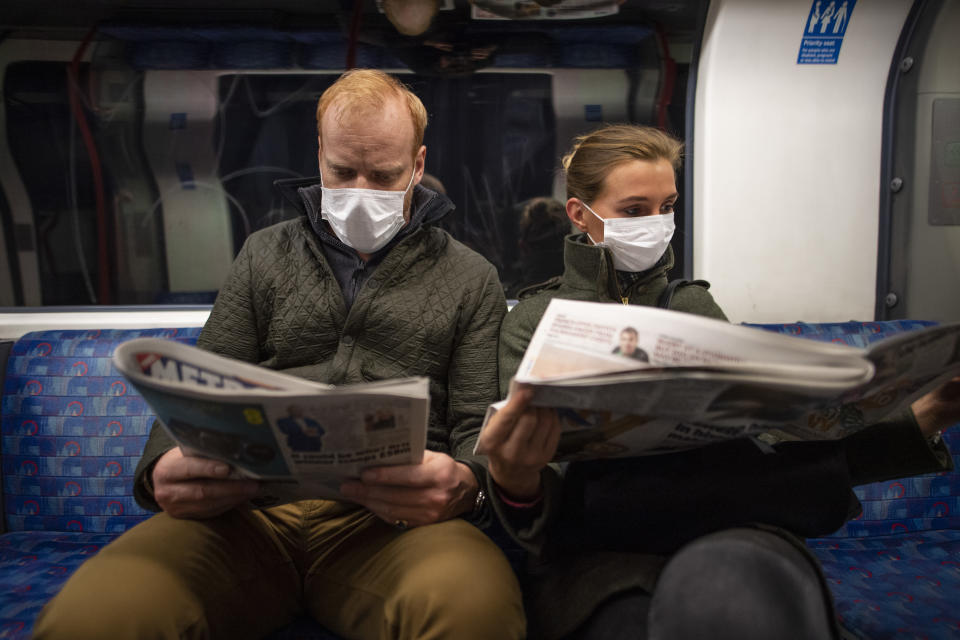 LONDON, ENGLAND - MARCH 19: A couple sit on the Central Line Tube wearing protective face masks while reading a newspaper on March 19, 2020 in London, England. Transport for London announced the closure of up to 40 stations as officials advised against non-essential travel. Bus and London Overground service will also be reduced. (Photo by Justin Setterfield/Getty Images)